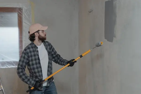 Painter rolling grey paint onto an interior wall in Cedar Rapids